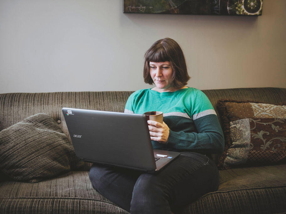 Woman sitting on her couch completing work on a laptop